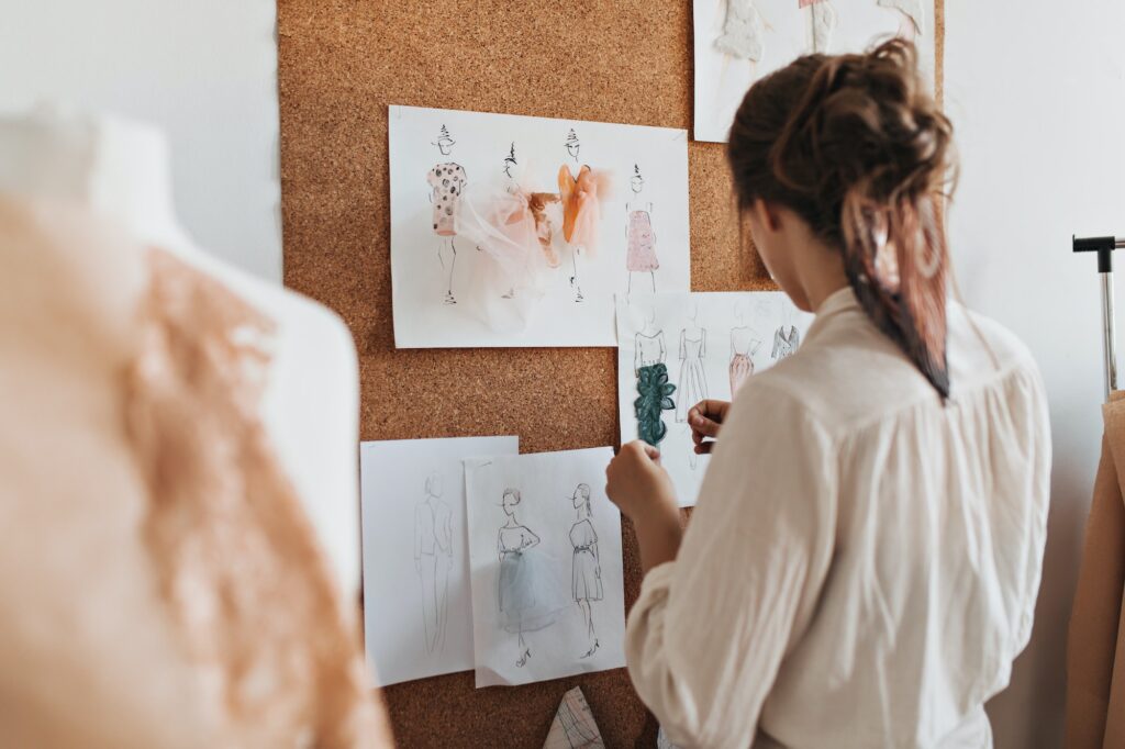 Woman designing dress and suits samples. Brunette lady in beige blouse creating stylish and colorfu